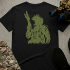 A black short-sleeve graphic T-shirt laid flat on a gray textured surface, surrounded by tactical-style props including camouflage pants, black shoes, and binoculars. The shirt features a large distressed olive-green graphic of a tactical soldier wearing combat gear and holding a rifle, creating a rugged military-inspired design.