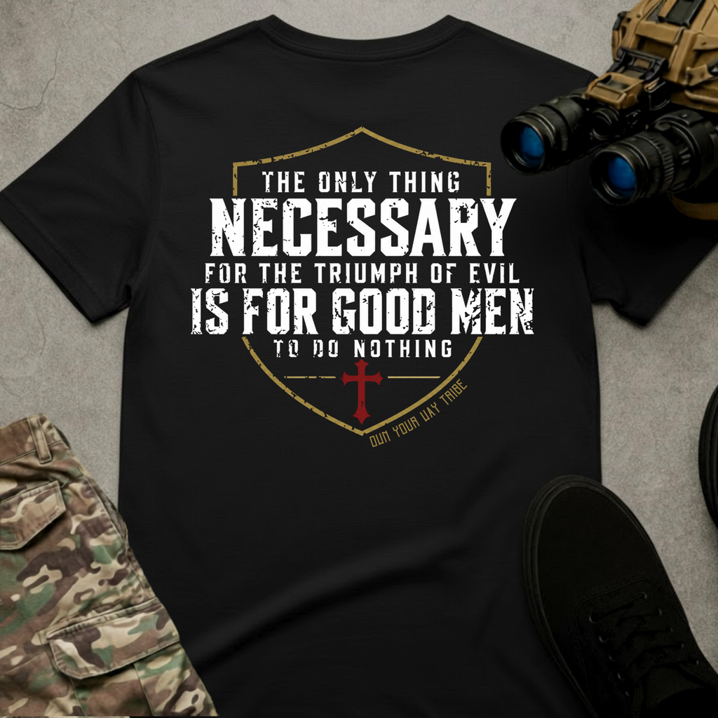 A black graphic t-shirt laid flat on a gray concrete-textured background, surrounded by tactical props including binoculars, camouflage pants, and black sneakers. The shirt features a distressed white and gold shield graphic with a red cross and the text 'THE ONLY THING NECESSARY FOR THE TRIUMPH OF EVIL IS FOR GOOD MEN TO DO NOTHING'.